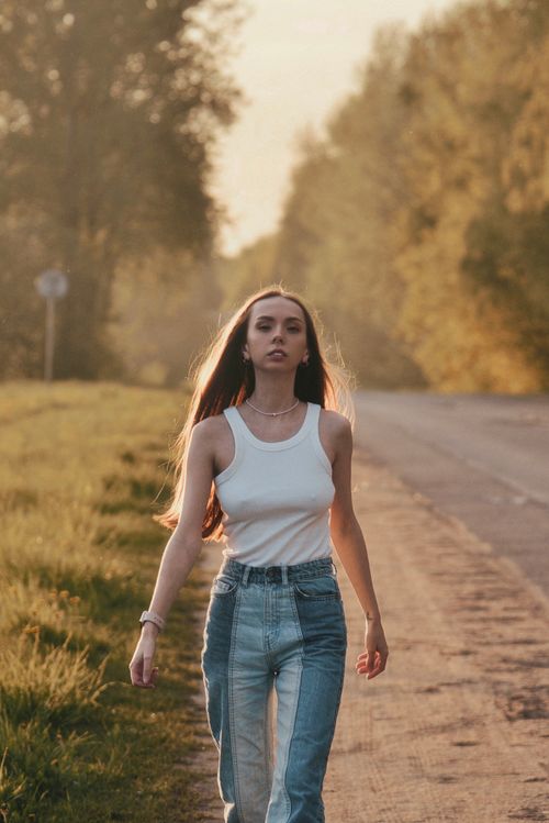 Free Young woman confidently walking down a rural road, embracing freedom and nature. Stock Photo