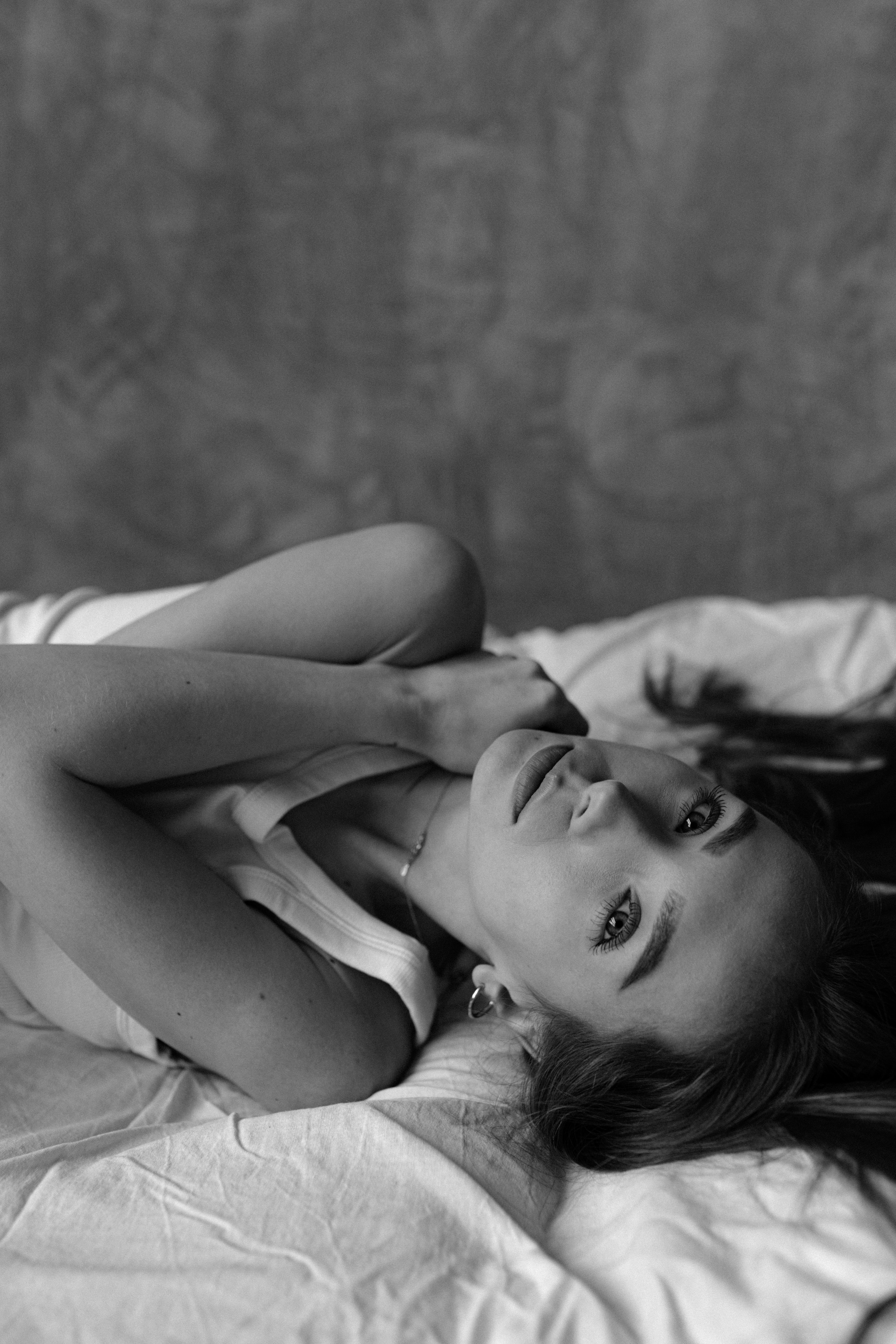 A woman laying on a bed in black and white · Free Stock Photo