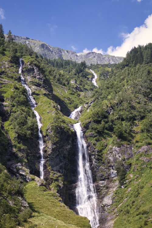 Free Majestic waterfalls cascading down rocky cliffs surrounded by lush green foliage. Stock Photo