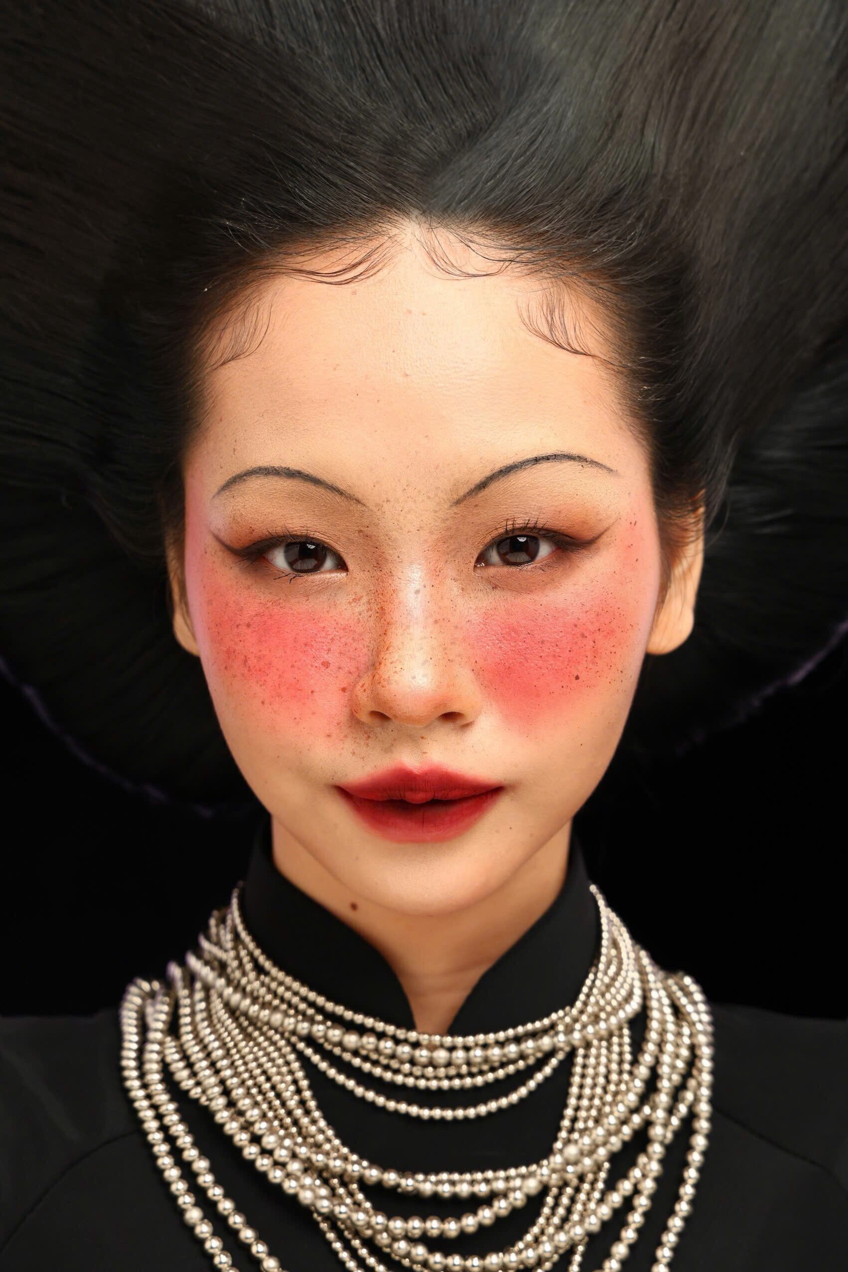 Portrait of an Asian woman with dramatic makeup and pearl necklace.