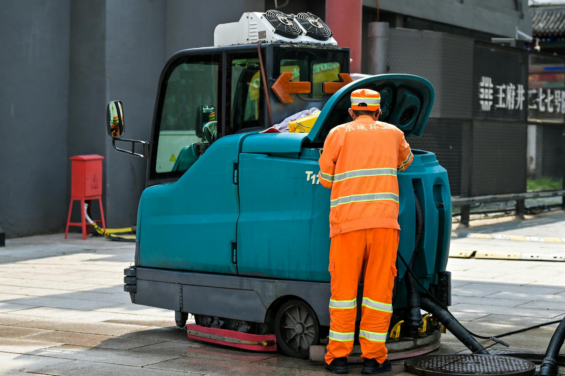 A man in orange work clothes cleaning a street