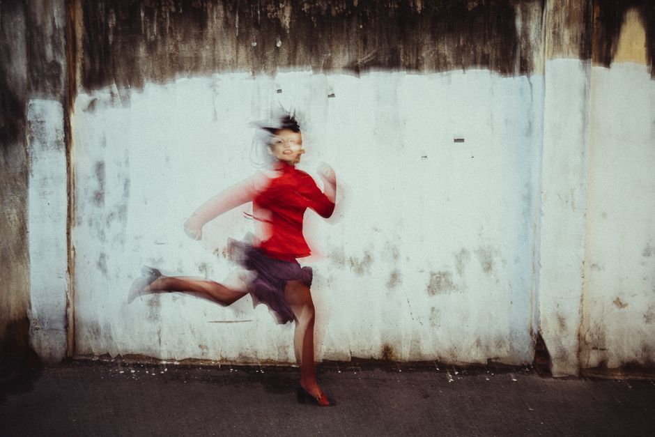Artistic portrait of a woman running against an urban wall with motion blur effect.