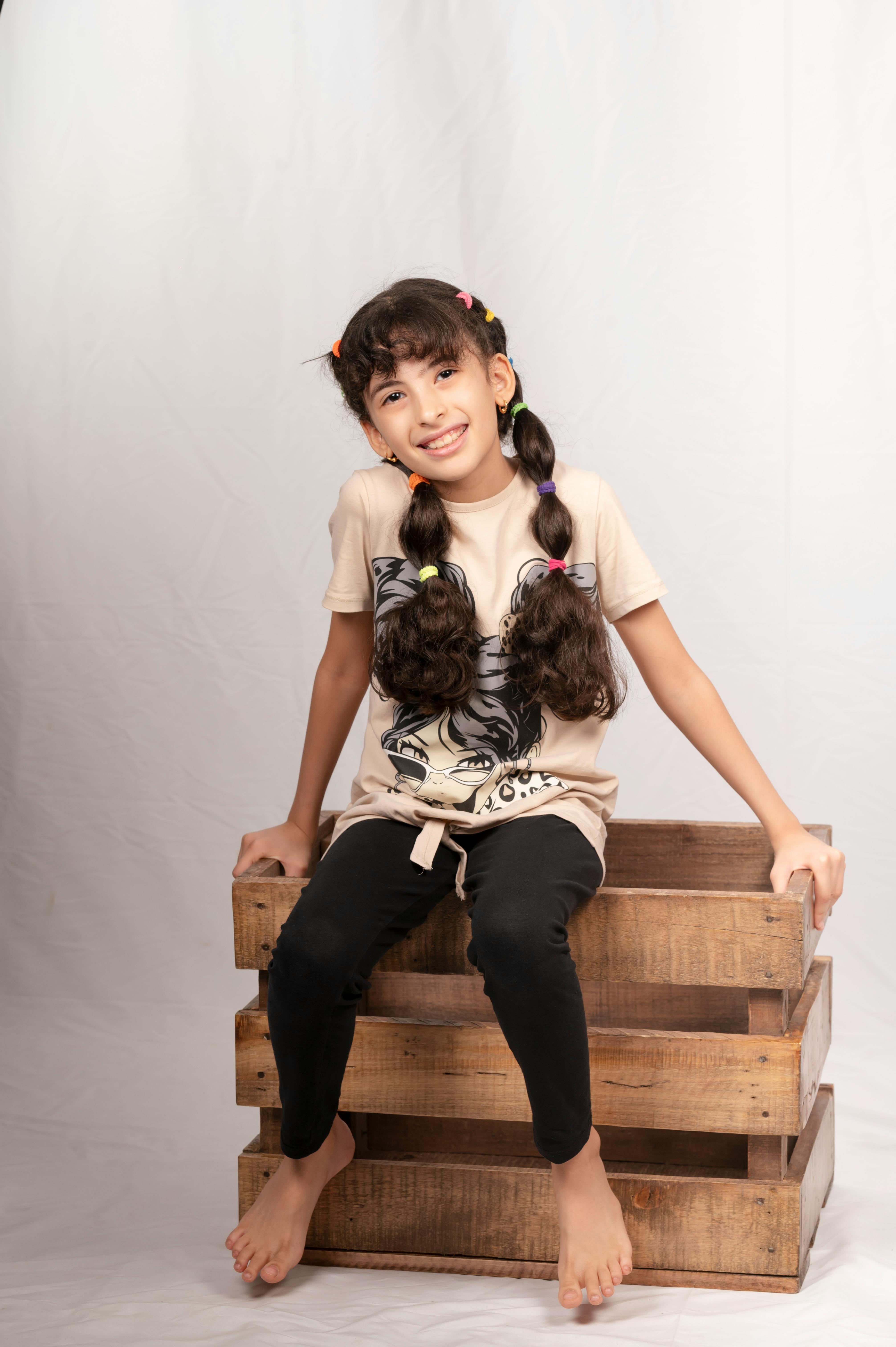 a little girl sitting on a wooden crate