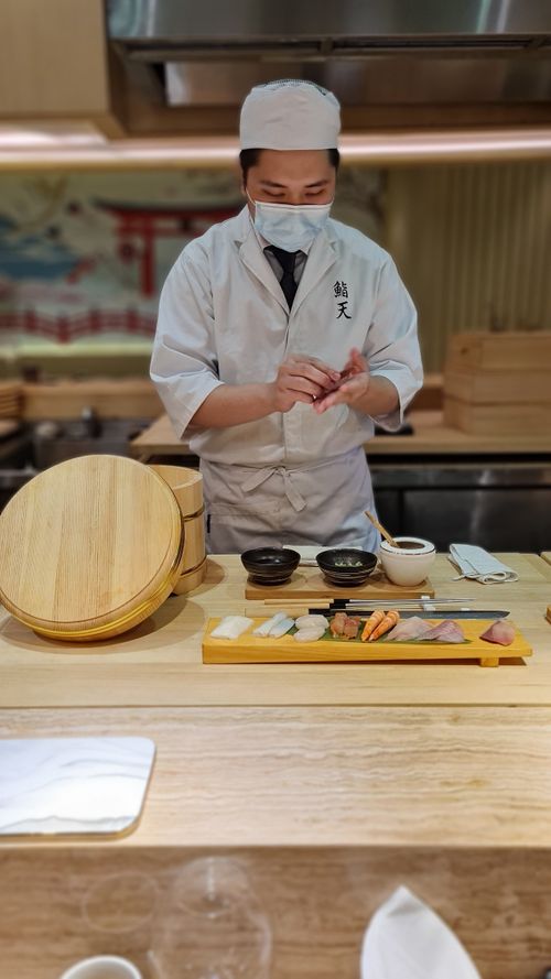Free Skilled Japanese chef prepares sushi at restaurant counter, showcasing culinary expertise. Stock Photo