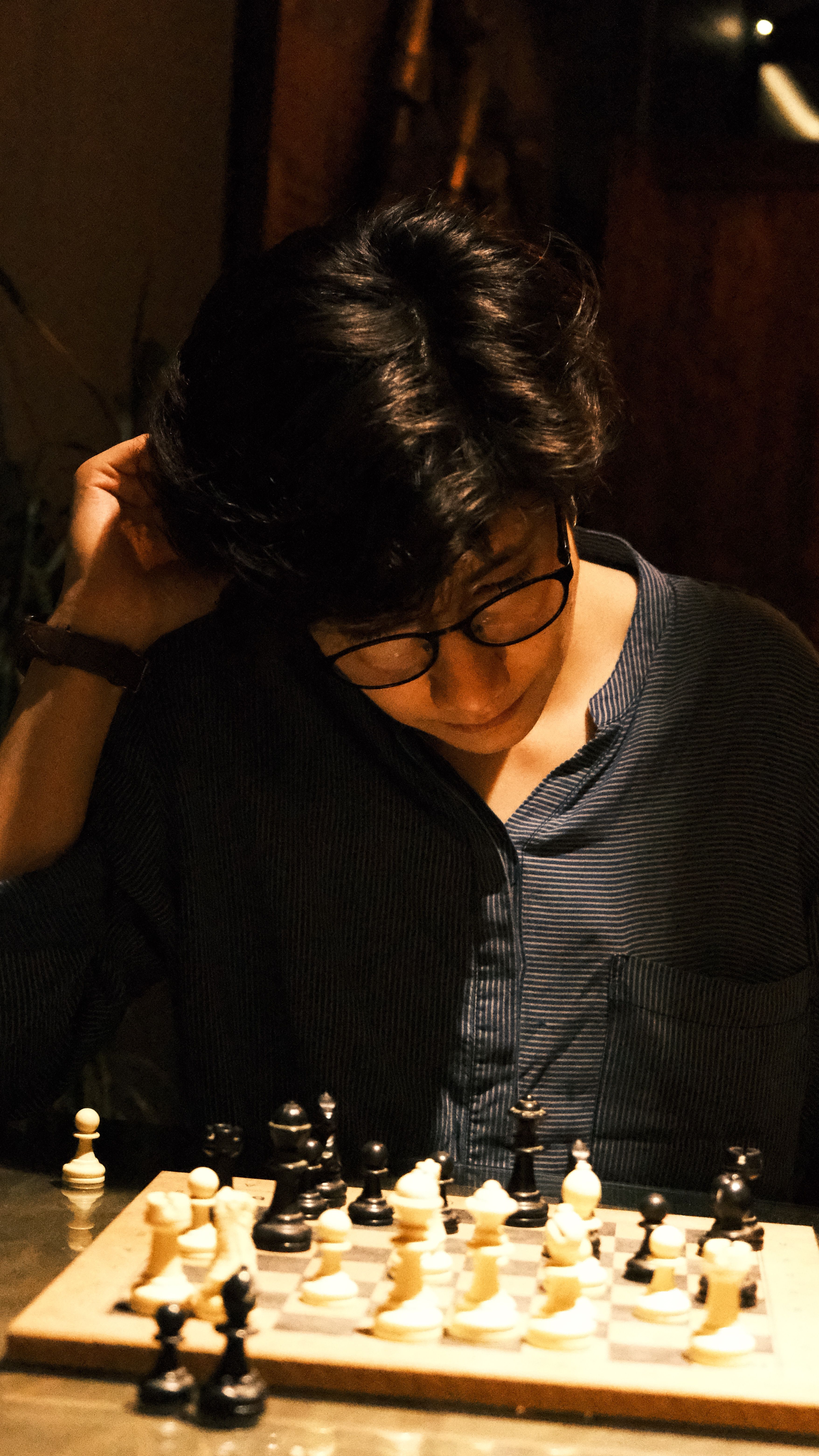 A person intensely concentrating on a chess game indoors, showcasing strategy and thoughtfulness.
