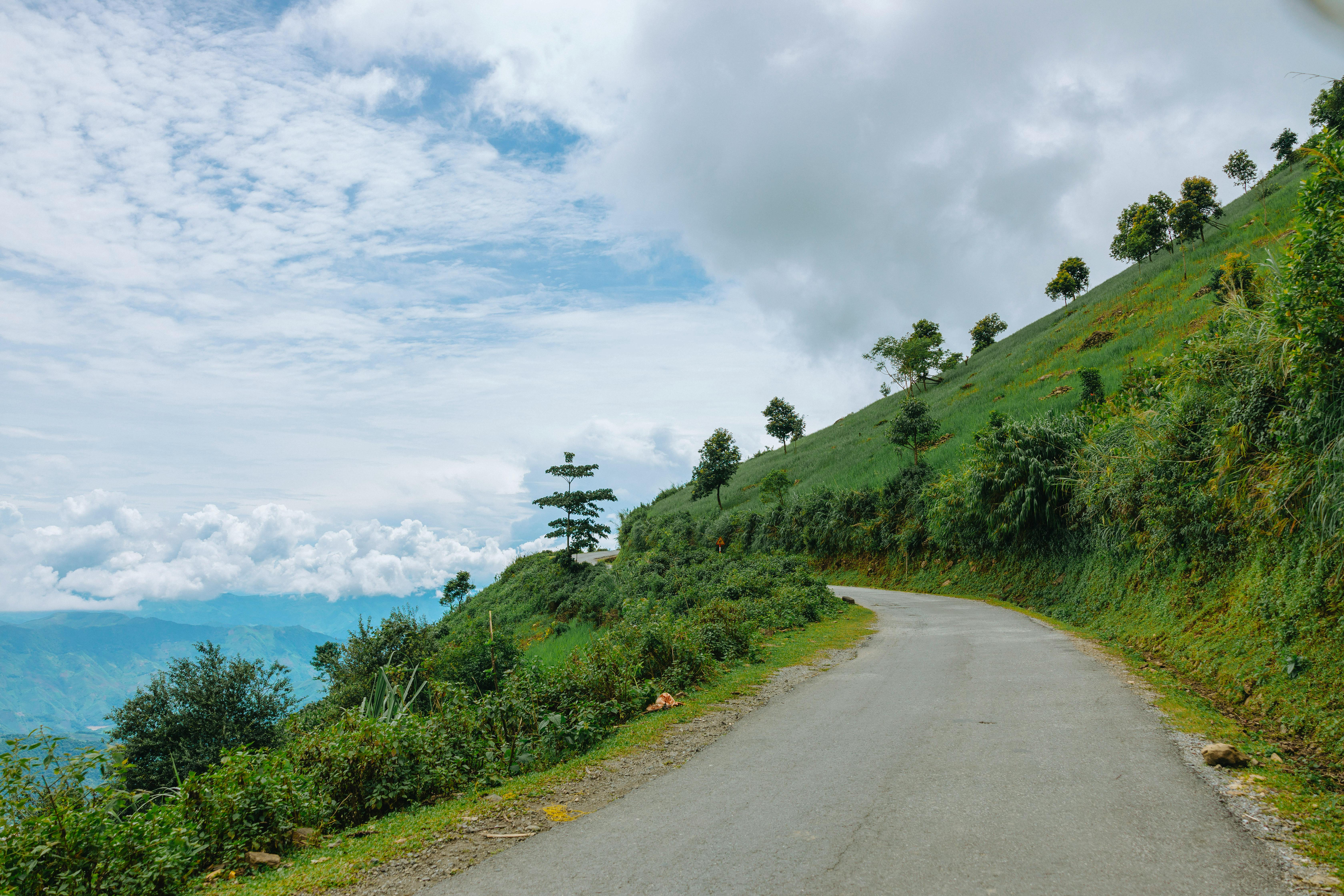 A winding road on a hillside with lush green grass