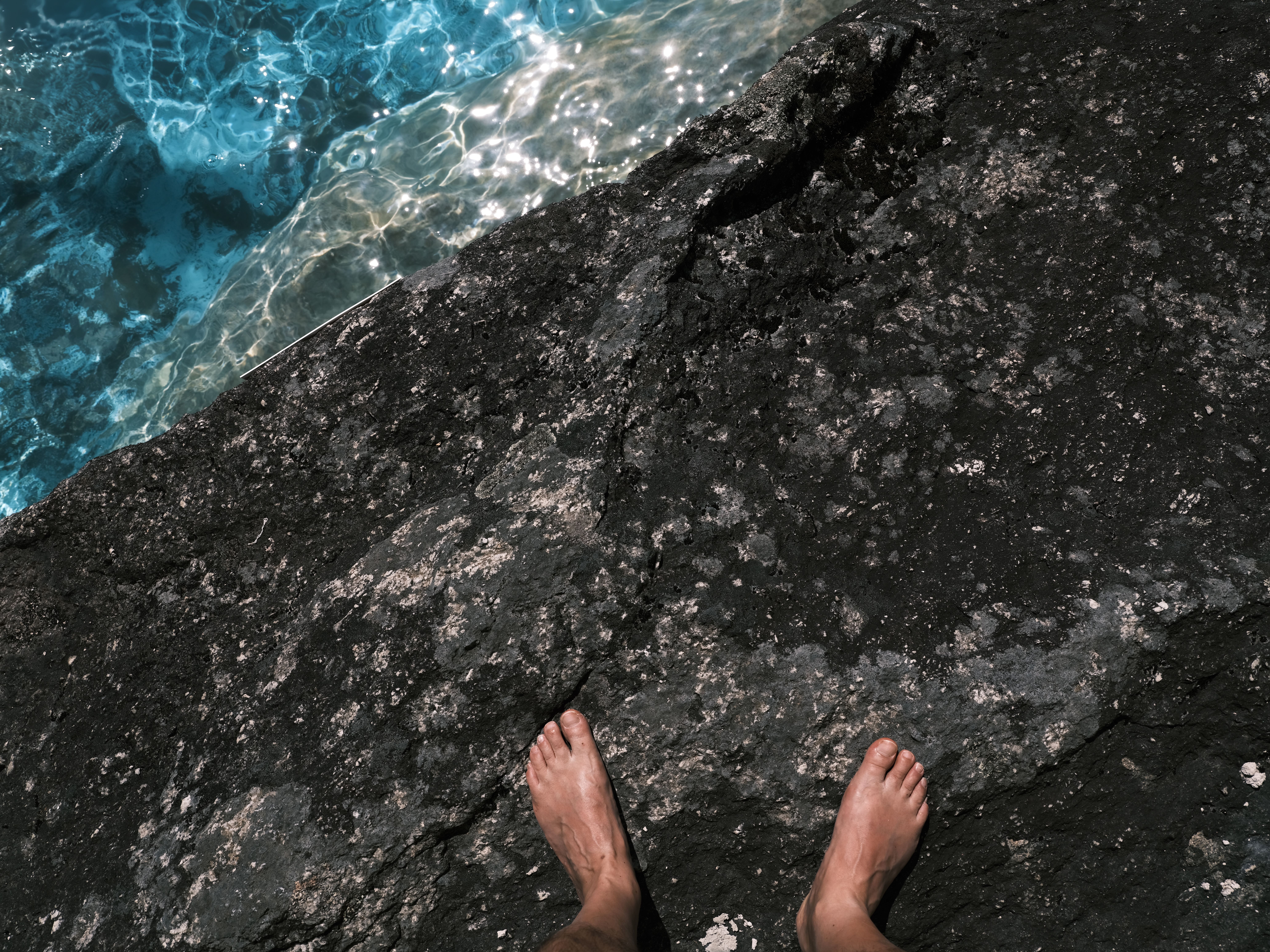 A person's feet on a rock in the ocean · Free Stock Photo