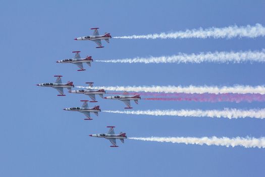 A group of fighter jets performing aerobatics with smoke trails in a clear sky.