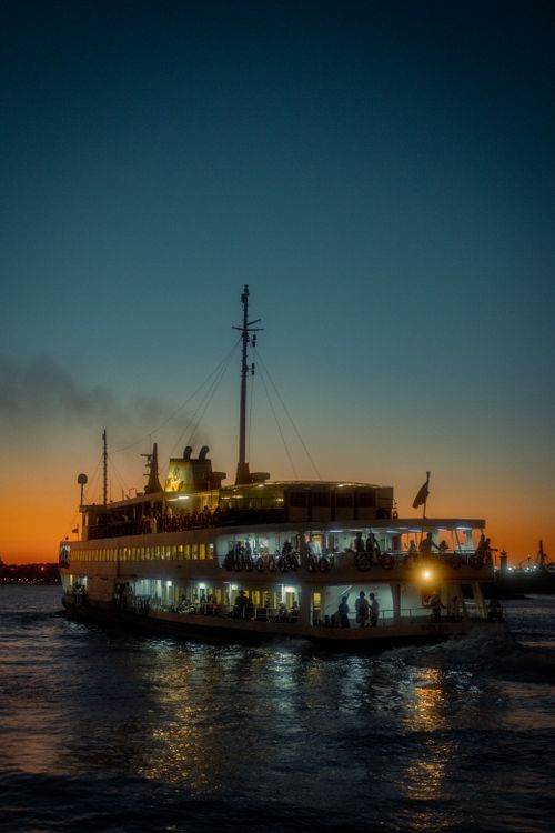 Free A passenger ferry sails at sunset, reflecting light on calm waters. Stock Photo