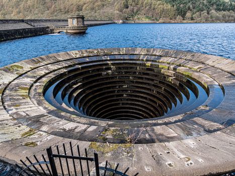 A circular hole in the ground with water flowing out of it