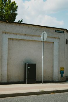 Minimalist urban landscape with a textured wall and street sign on a sunny day.