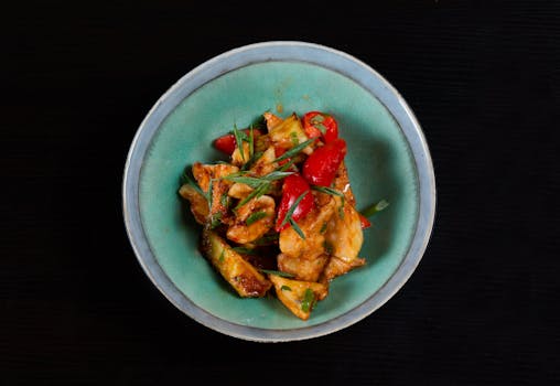Delicious spicy chicken stir fry with colorful peppers served in a bowl. Perfect for a flavorful meal.
