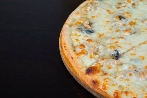 Free Close-up of a freshly baked cheese pizza on a wooden board, perfect for dinner. Stock Photo