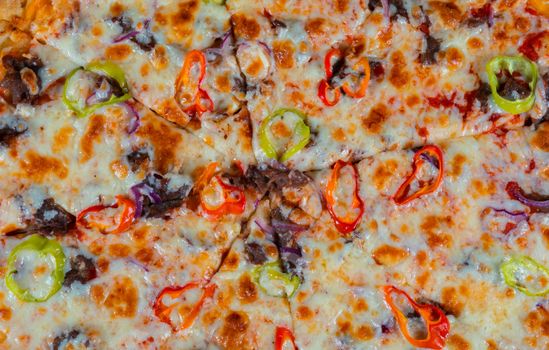 Close-up of a cheesy pizza topped with colorful peppers and meat slices.