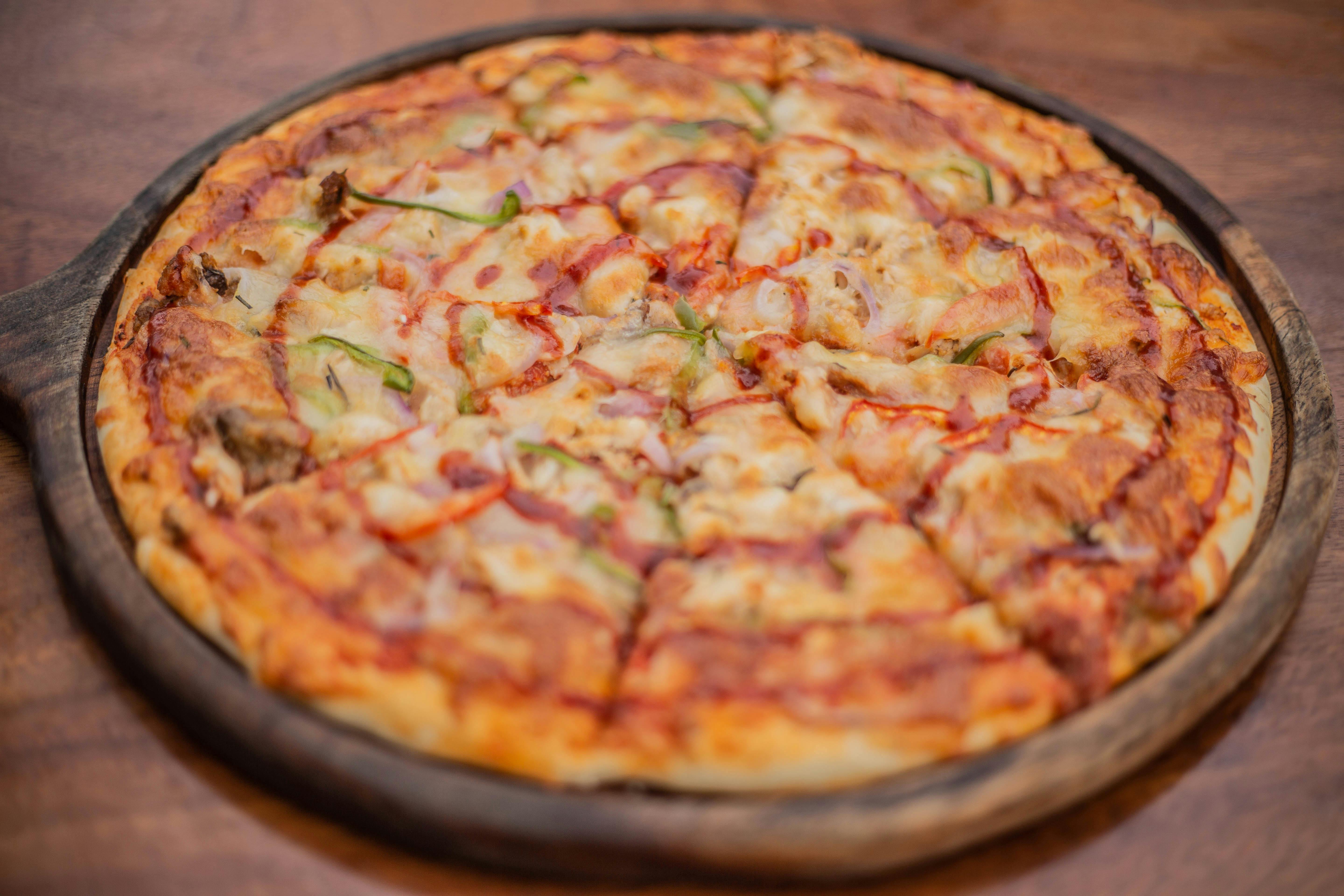 a pizza on a wooden plate with cheese and vegetables