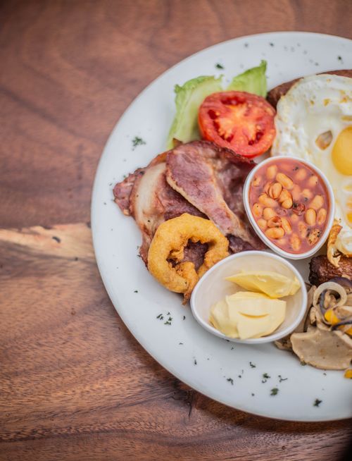 Free Scrumptious English breakfast featuring eggs, bacon, beans, and more on a rustic wooden table. Stock Photo