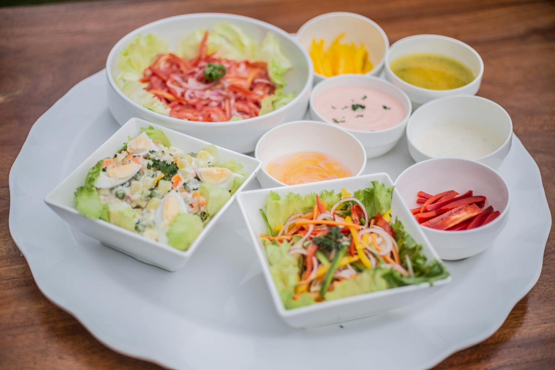 https://www.pexels.com/photo/a-white-plate-with-several-bowls-of-salad-and-sauces-27583274/