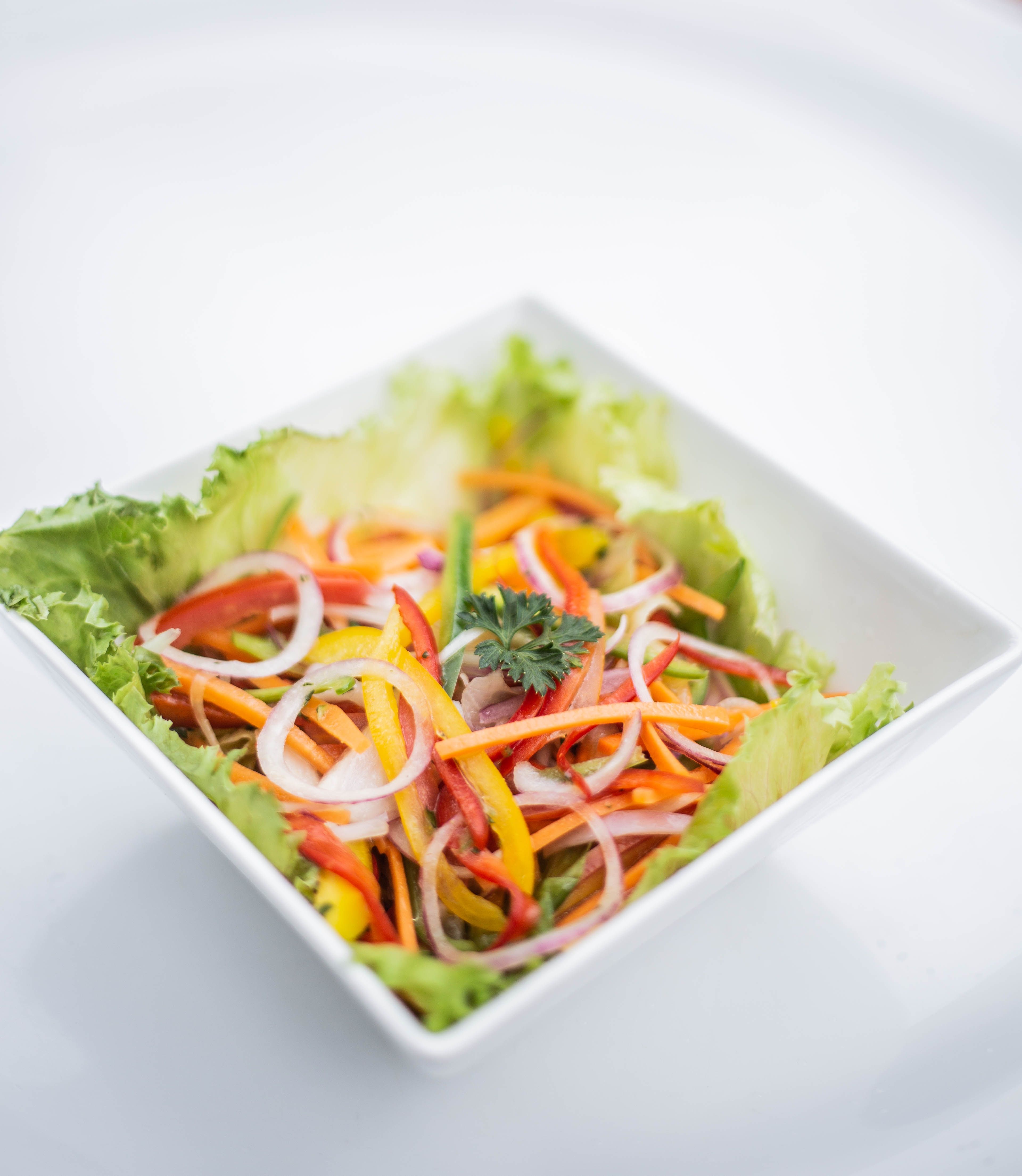 Colorful vegetable salad with lettuce, peppers, and onions in a white bowl provides a healthful dining option.