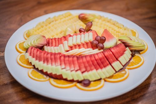 Free A colorful fruit platter featuring watermelon, pineapple, apples, and grapes arranged artfully on a white plate. Stock Photo