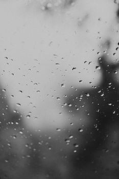Black and white photo of rain droplets on window creating a moody and abstract effect.