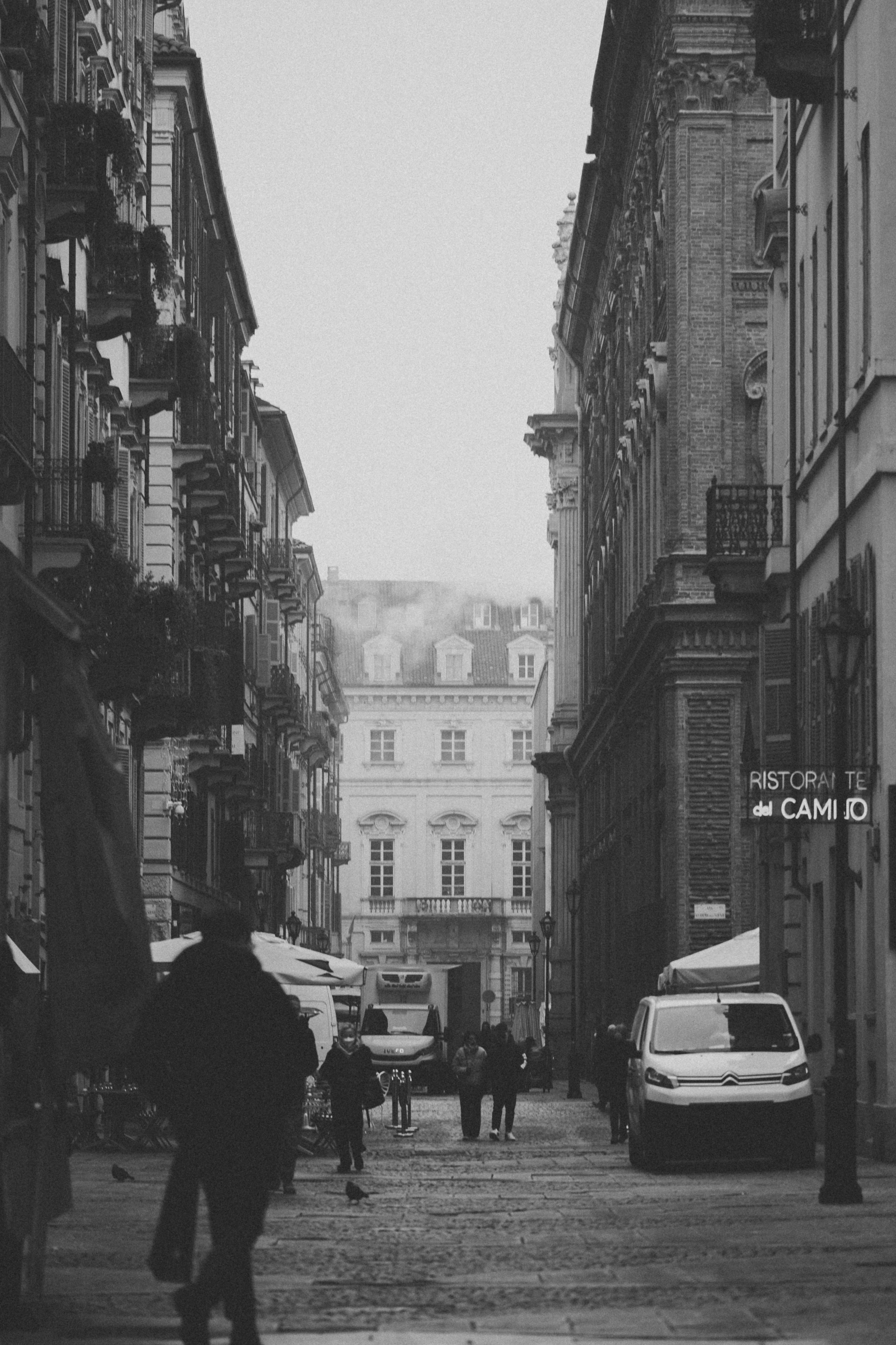 Black and white vintage photo capturing a European street scene with pedestrians and classic architecture.