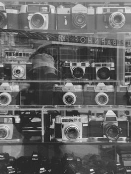 A nostalgic black and white photo of vintage cameras displayed in a shop window.
