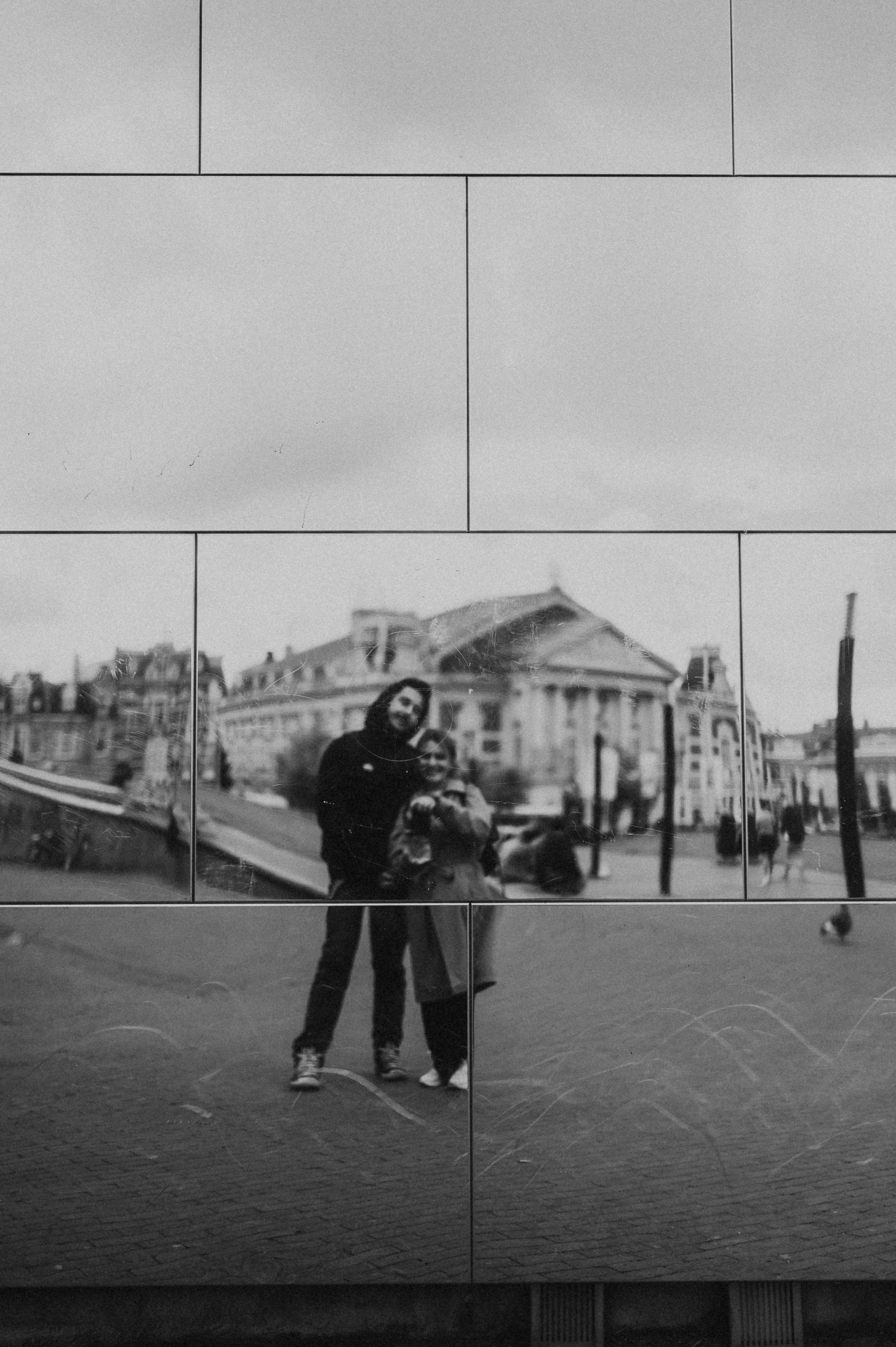 A black and white reflection of a couple with a classical building in the background.