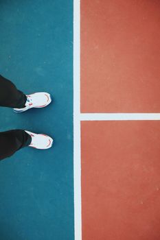 Person standing on a vibrant tennis court line, showcasing sporty sneakers and color contrast.