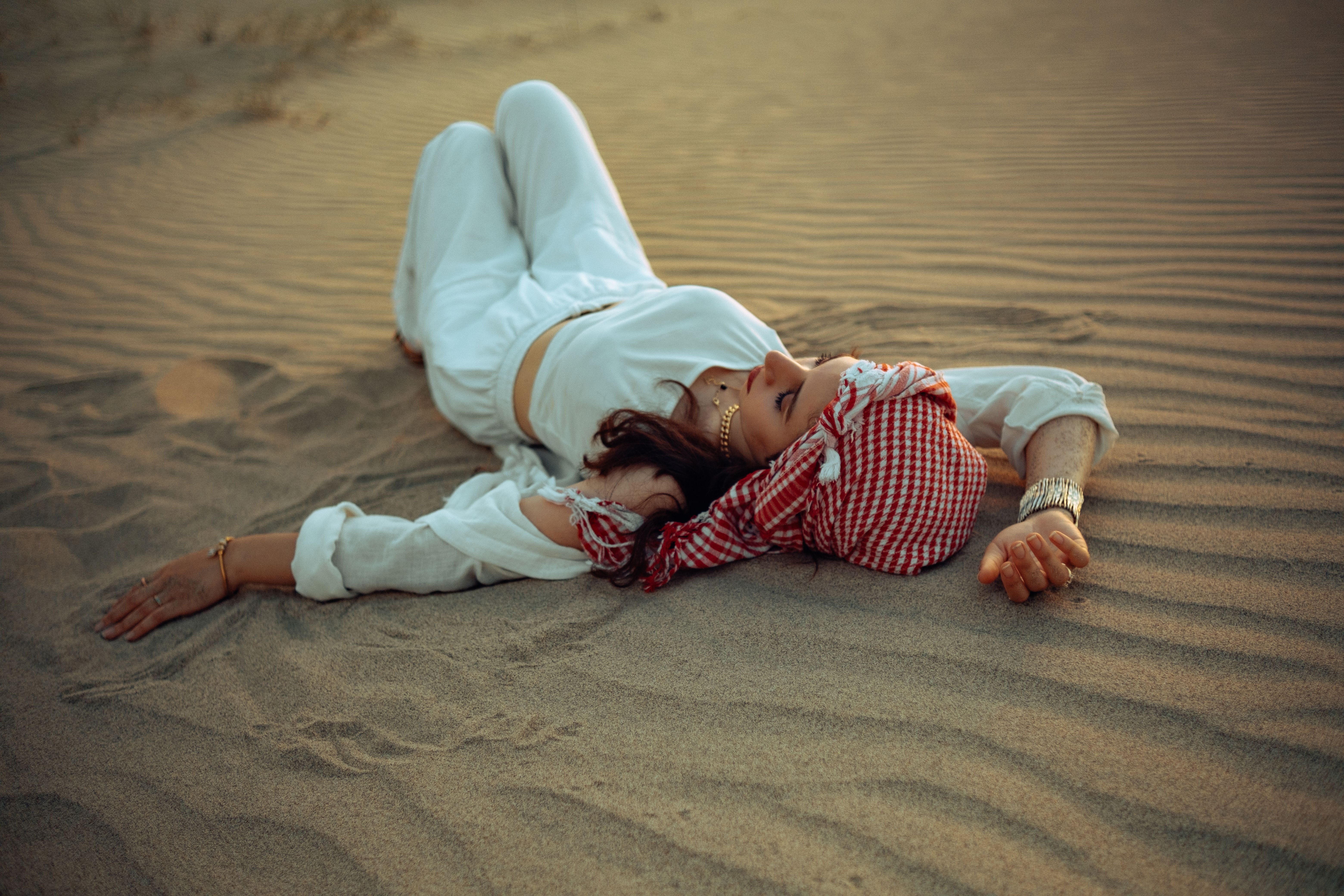 A woman laying on the sand in the desert · Free Stock Photo