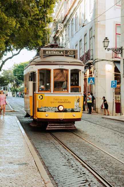 Iconic yellow tram on Lisbon's cobblestone streets, a popular tourist attraction.