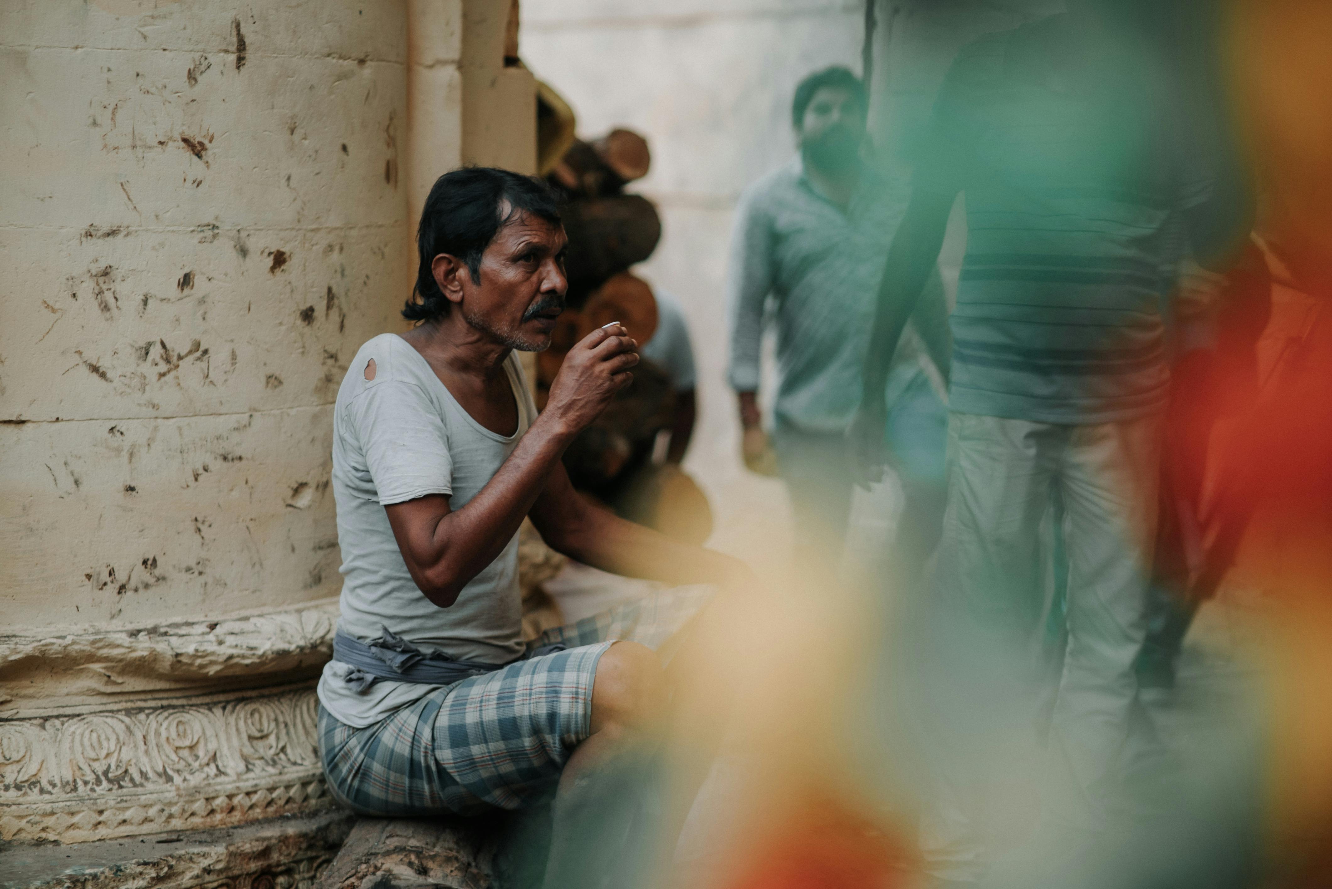 a man sitting on the ground smoking a cigarette