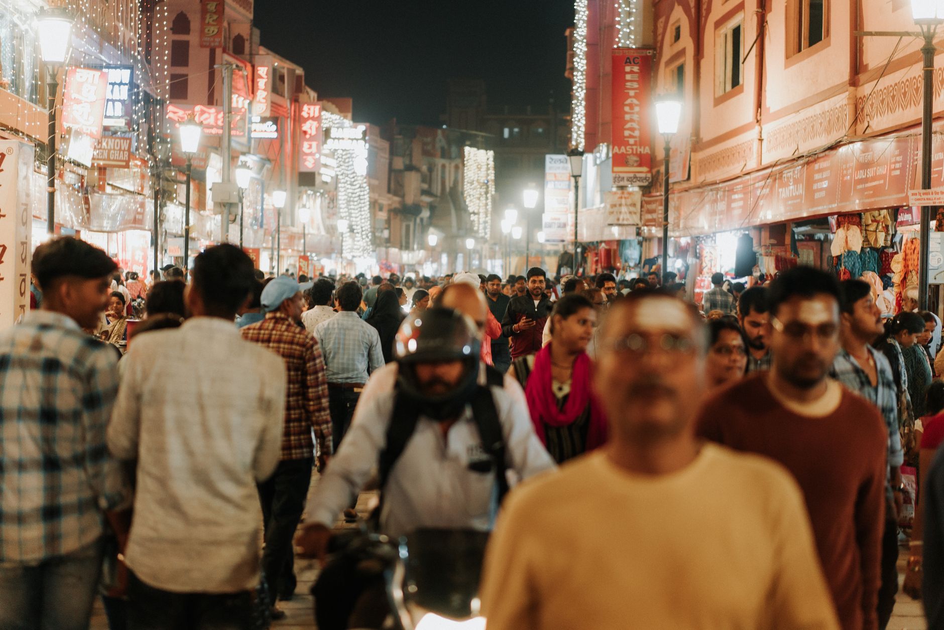 Bustling night market with crowd and vibrant lights in an urban street setting.