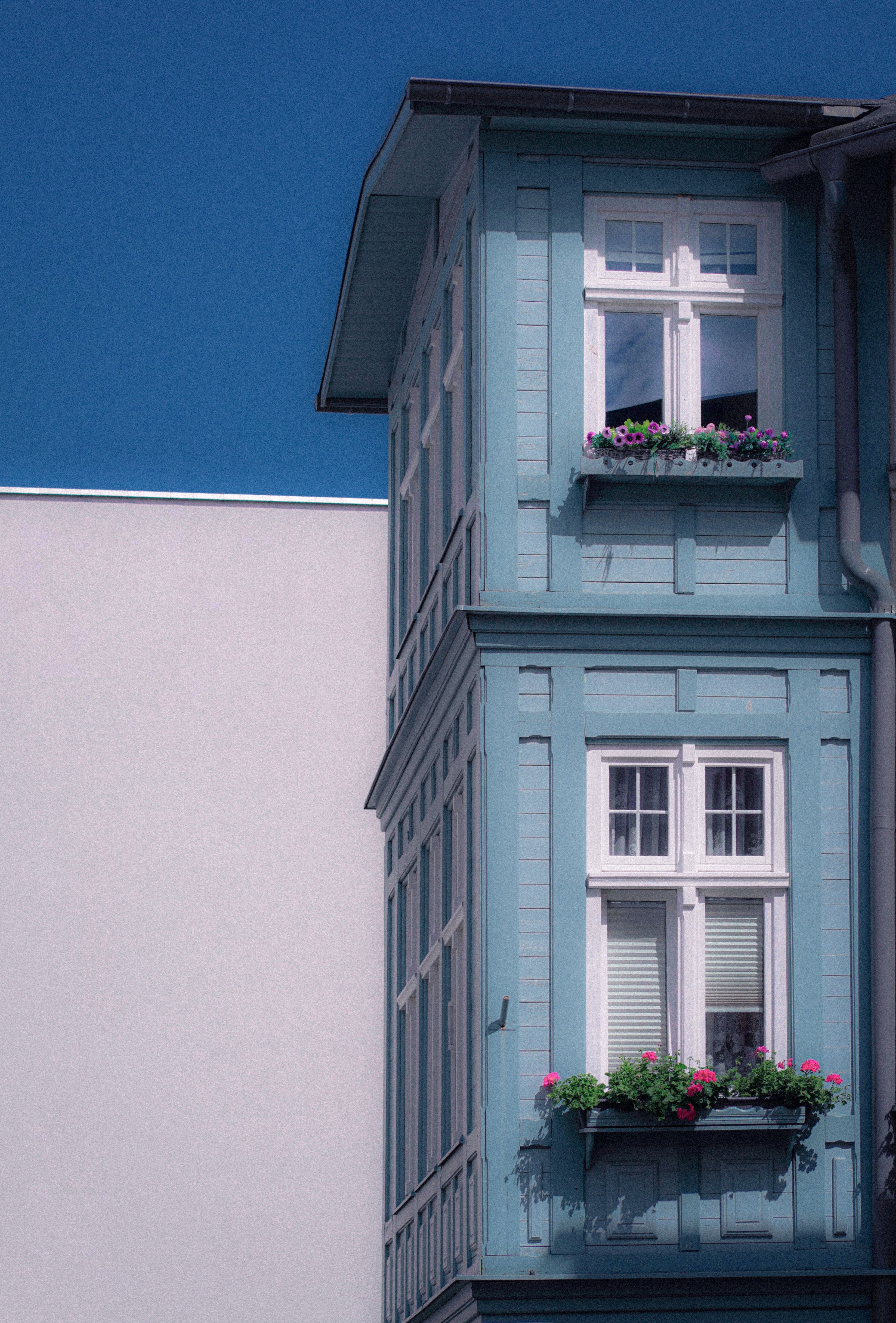 A blue house with a balcony and flowers in the windows · Free Stock Photo