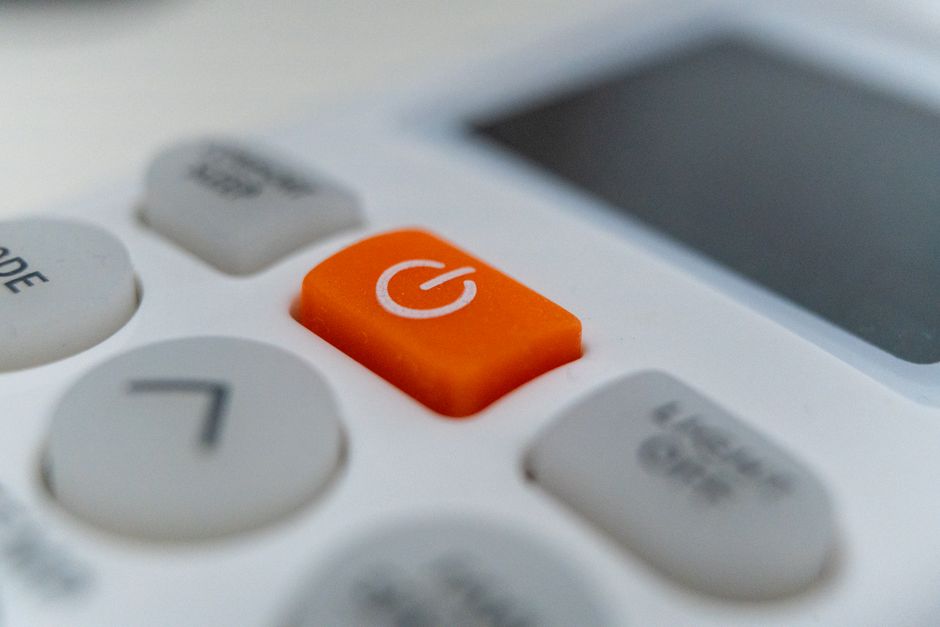 Detailed view of an orange power button on an electronic remote control device.