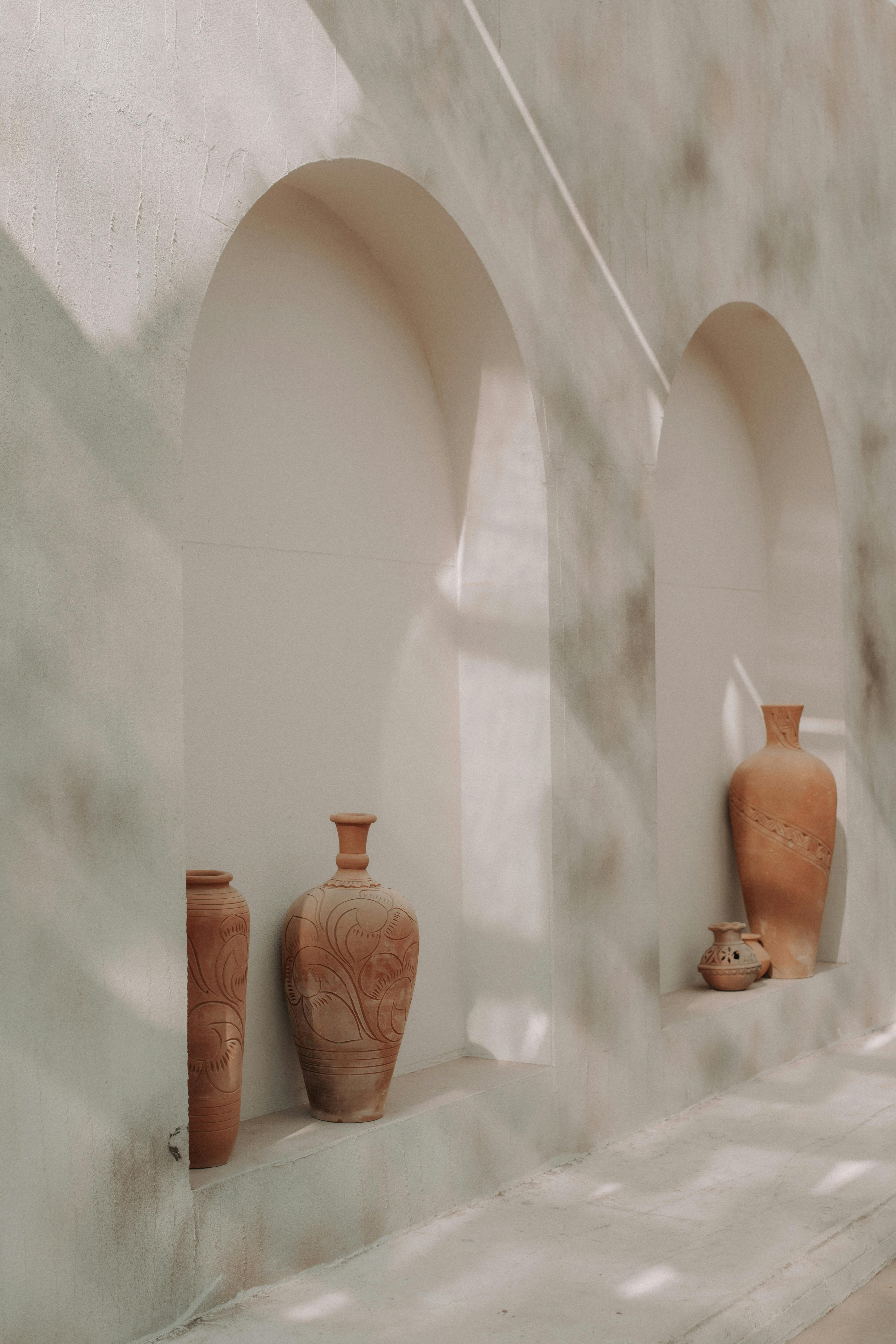 Three terracotta pots in a sunlit niche of an ancient stone building