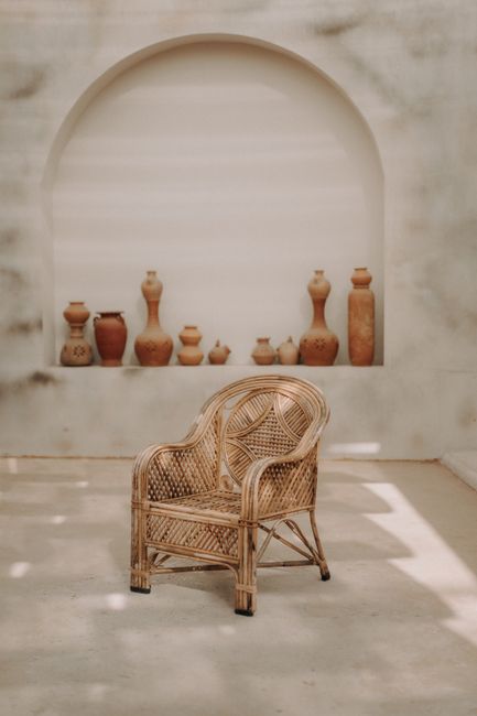 A stylish wicker armchair poses in a minimalist interior with clay vases and artistic decor.