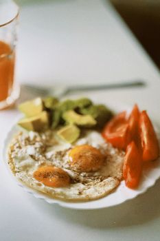 Tasty breakfast with fried eggs, avocado, and tomatoes. Perfect start to the day.