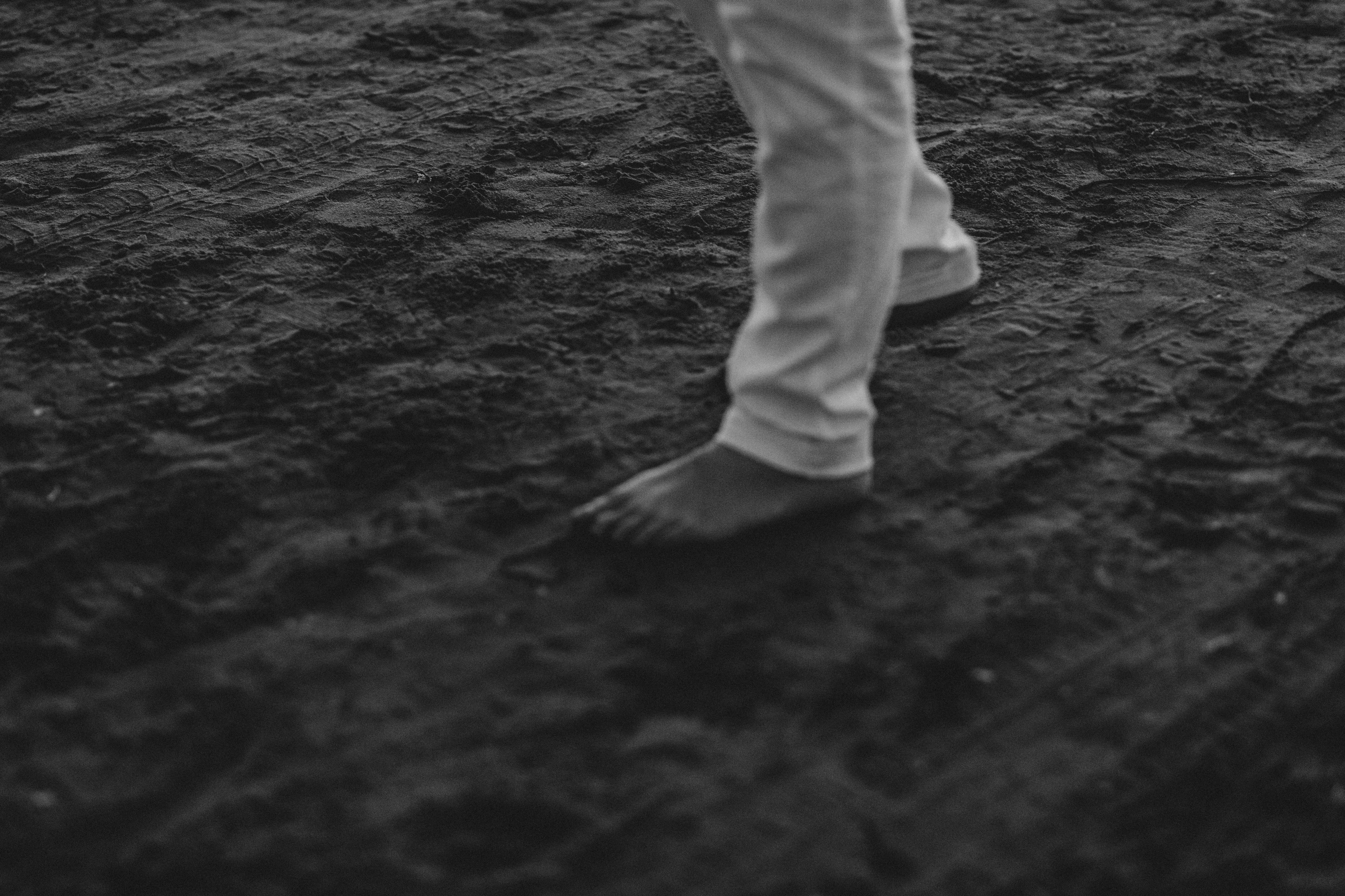 A striking black and white image featuring a bare foot on dark sand, exuding a minimalist vibe.