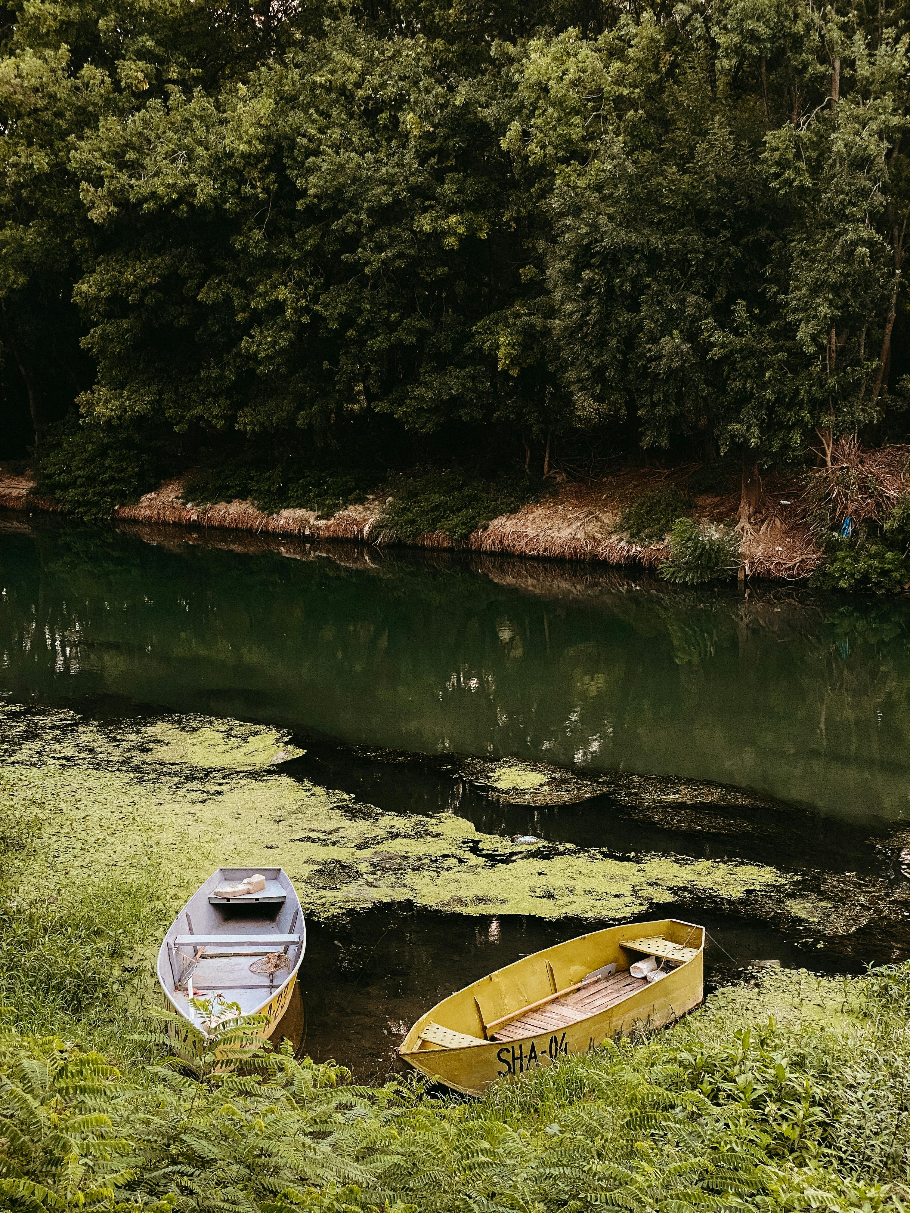 Peaceful riverside with two boats and lush greenery, ideal for nature and travel themes.