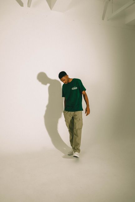 Portrait of a young man in a minimalist studio with shadow play on the wall.
