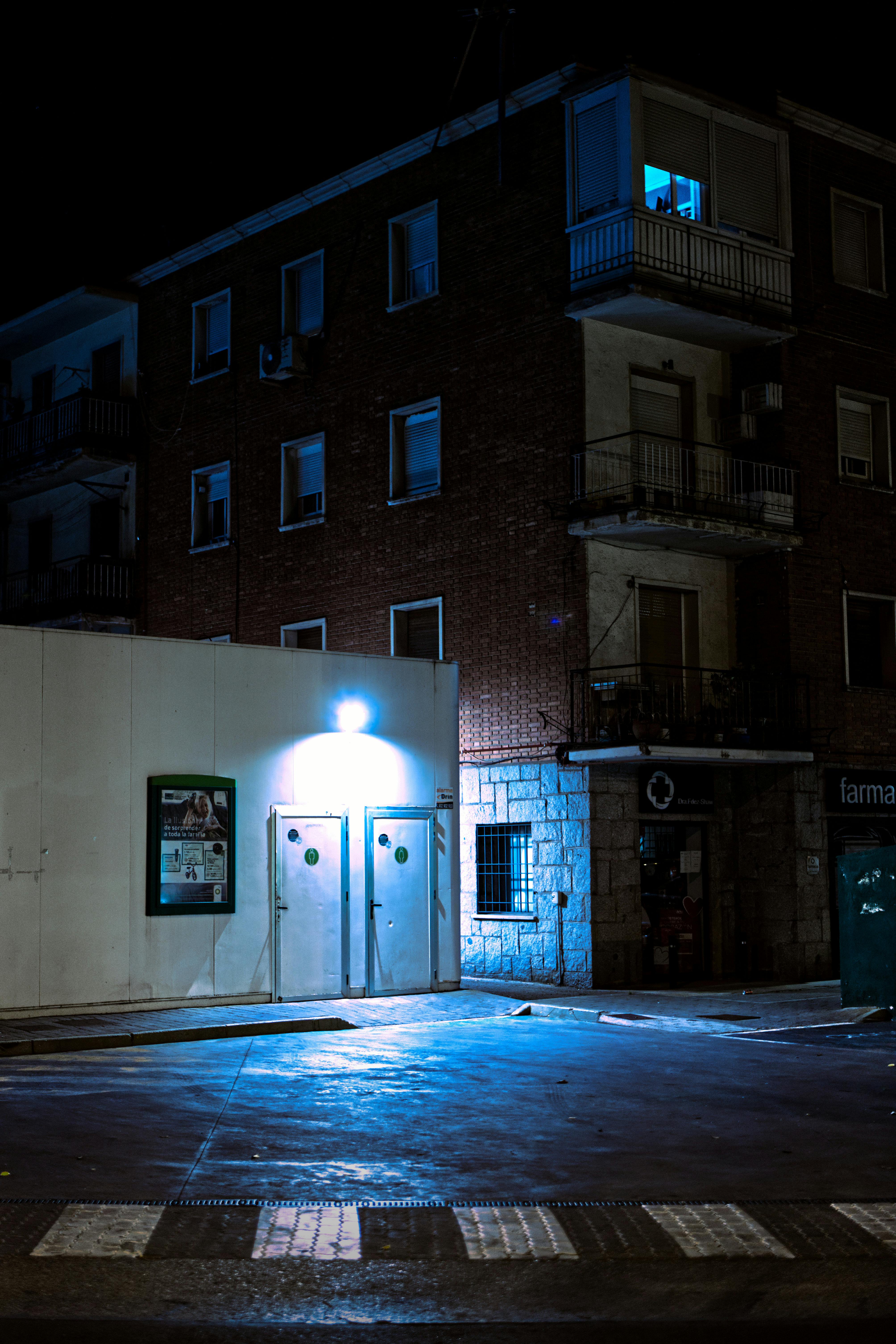 Free Moody night scene of an urban street with a lit building exterior and atmospheric lighting. Stock Photo