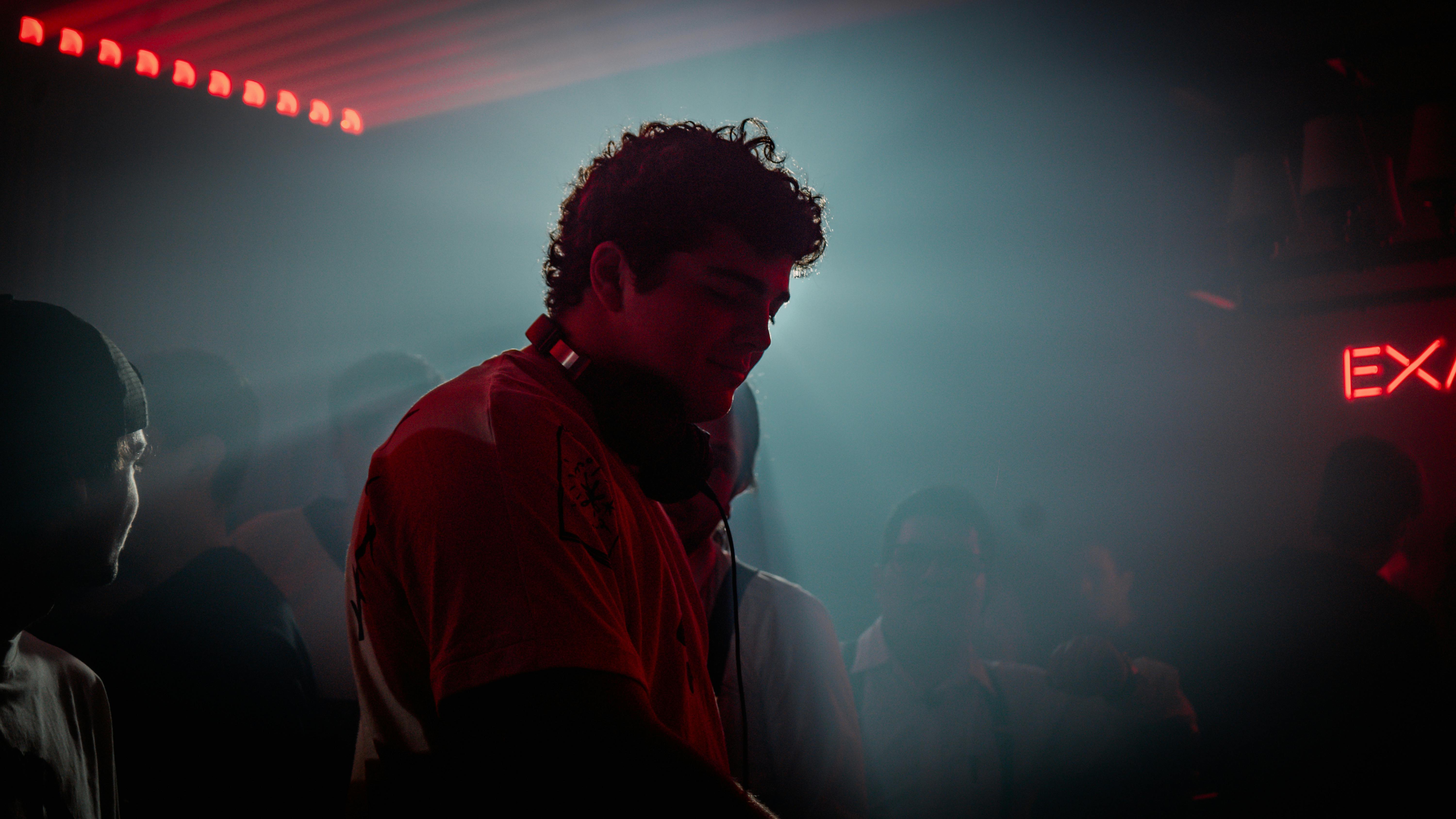 a man in red shirt standing in front of a dj booth