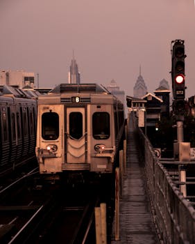 A train approaching the Philadelphia skyline during twilight, capturing urban transportation.