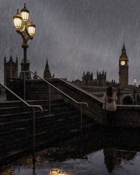 A person standing near Big Ben in London under a rainy sky at night.