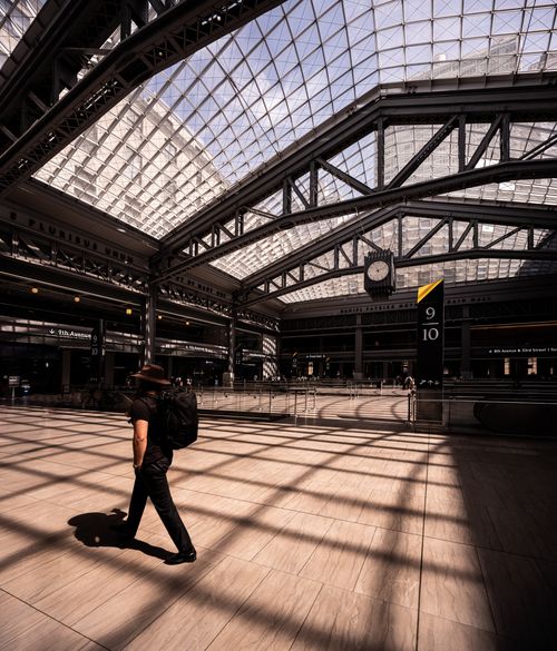 Free A lone commuter walks through the architectural beauty of Moynihan Train Hall in NYC. Stock Photo