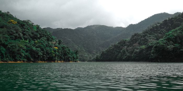 Tranquil view of a tropical lake surrounded by dense forests and mountains in Norcasia, Colombia.