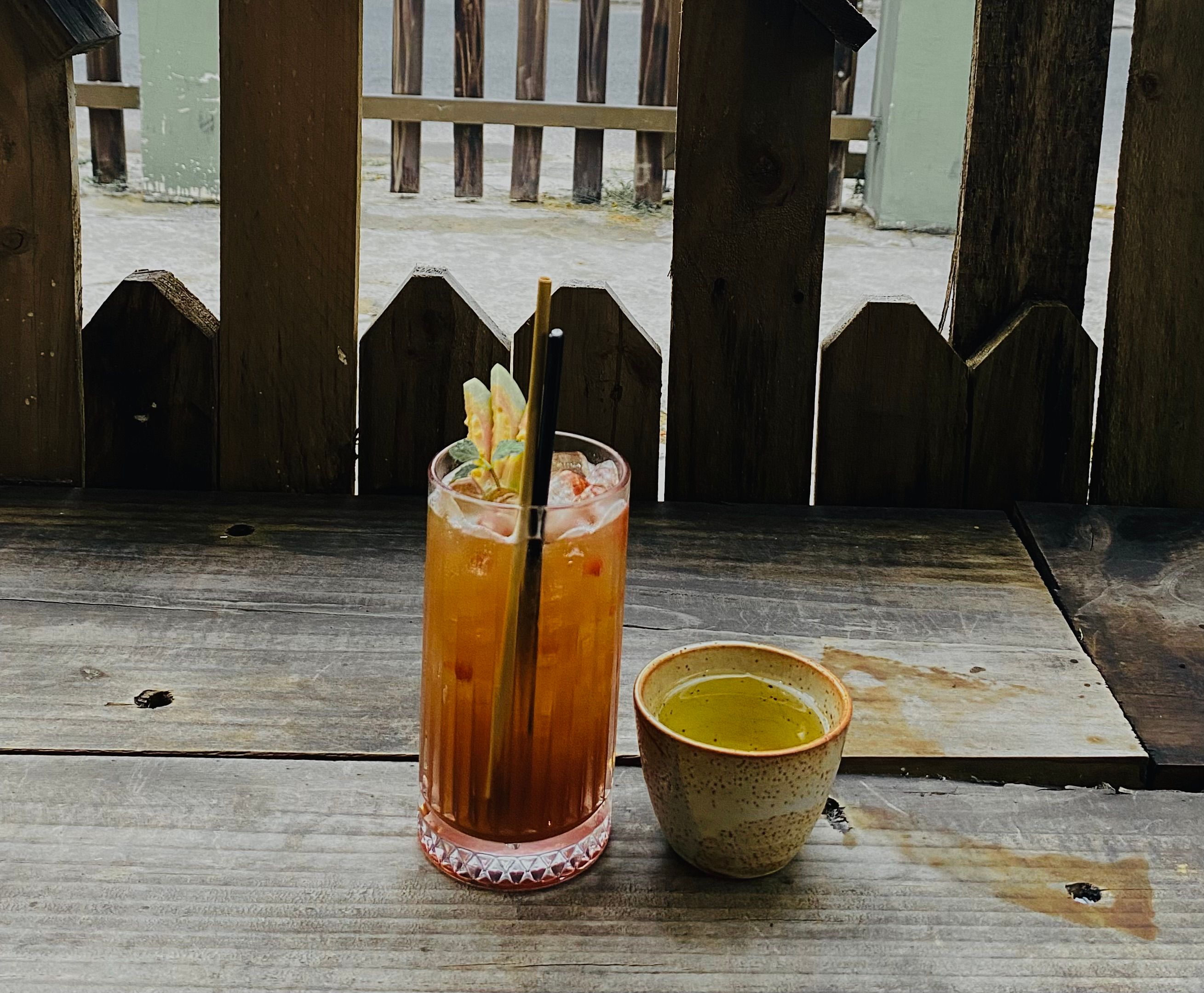 Glass of iced tea and cup of hot drink on a rustic wooden table outdoors in Binh Duong, Vietnam.