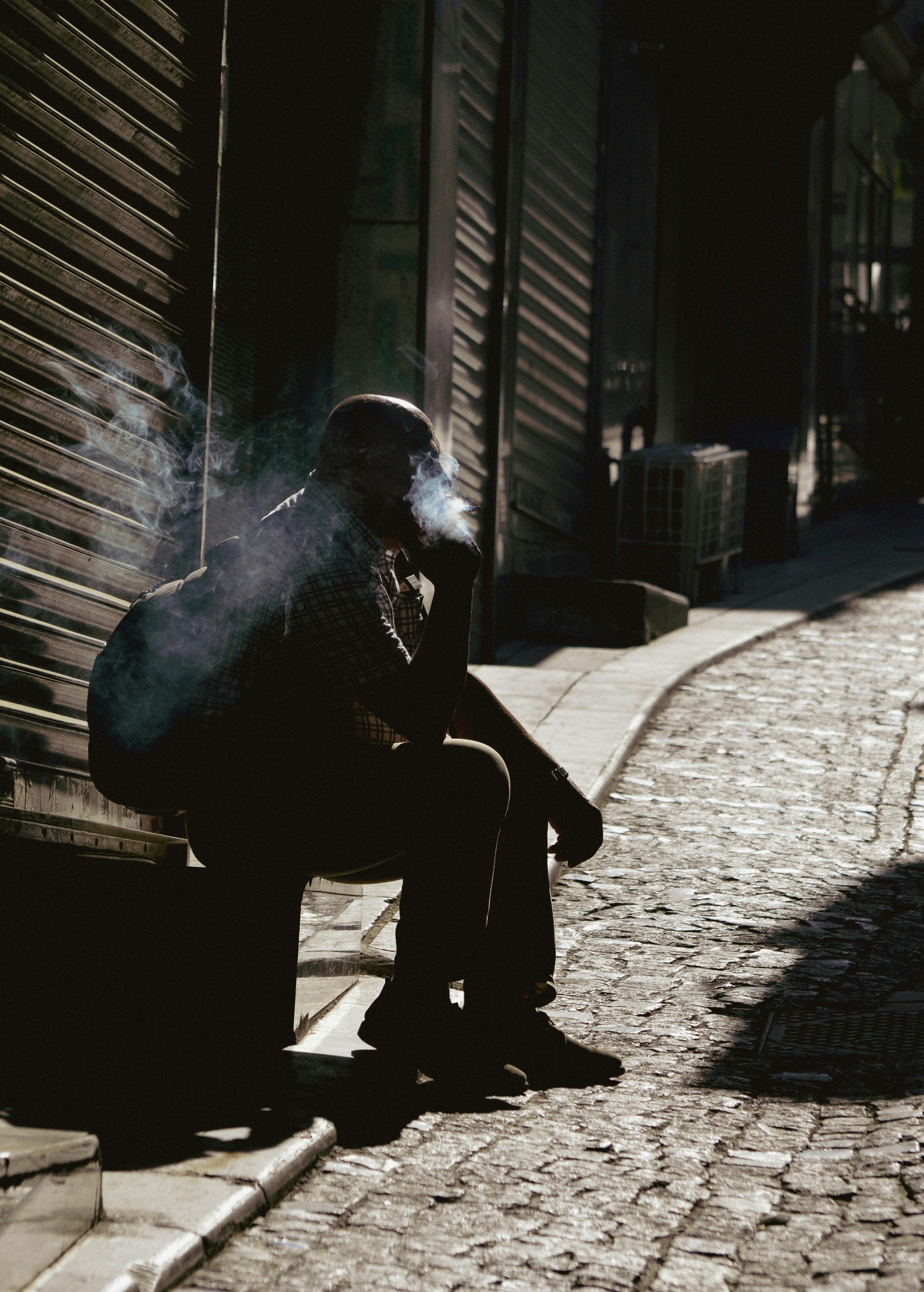 a man sitting on a bench smoking a cigarette