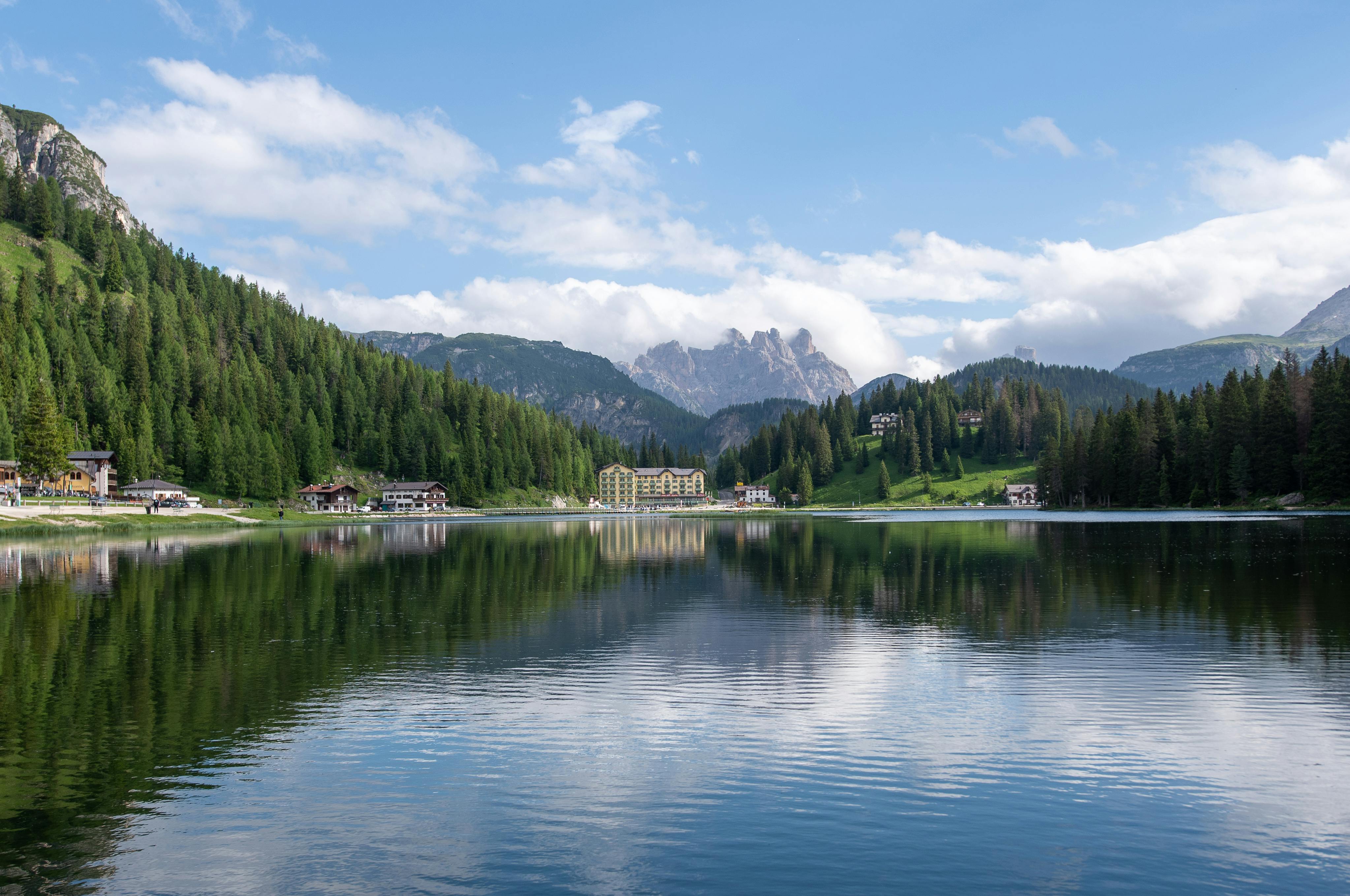 Sunrise over Misurina Lake in the Dolomites, golden light illuminating mirror-like alpine waters with Sorapiss peak reflected at dawn