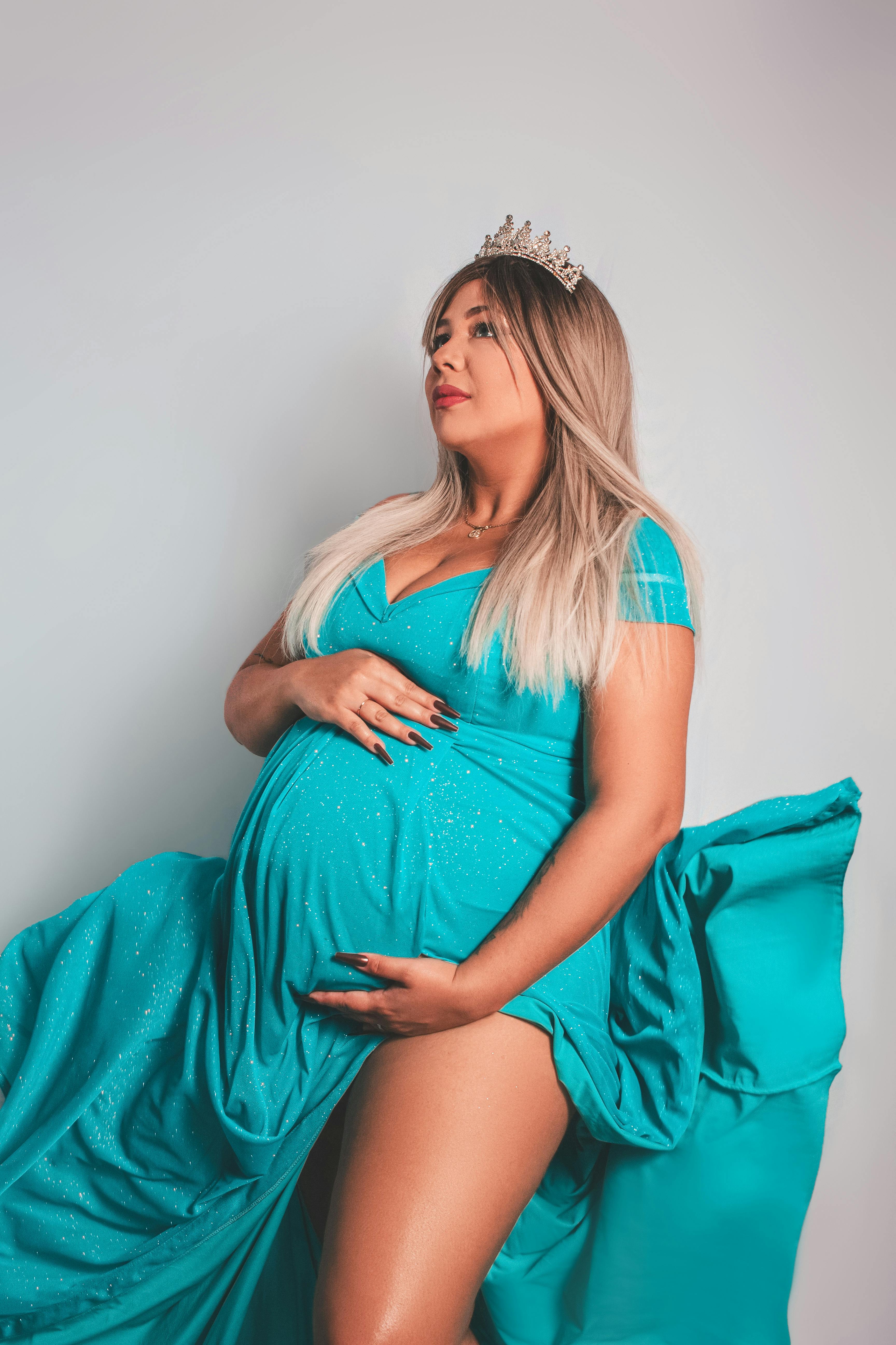 a pregnant woman in a blue dress posing for a photo